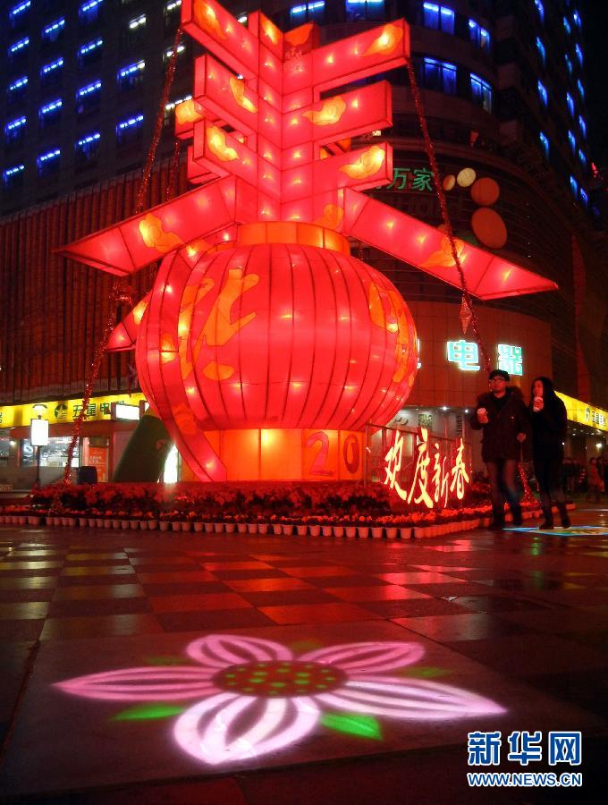 　1月30日晚，市民从苏州市石路银河广场上大型“春”字彩灯景观旁经过。