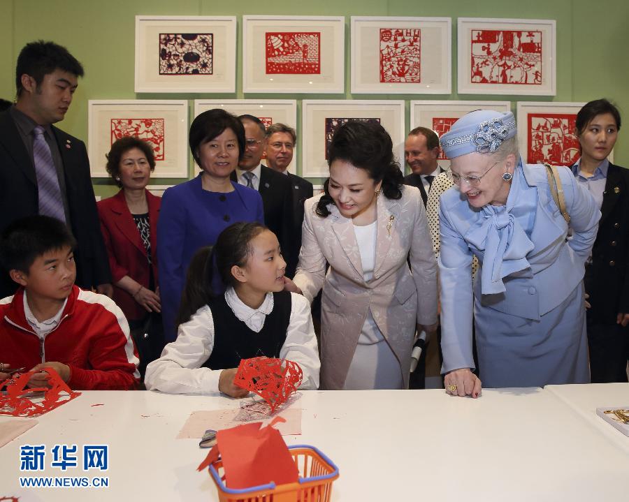 这是彭丽媛和玛格丽特二世与根据安徒生童话中人物和情节制作剪纸的孩子交谈。