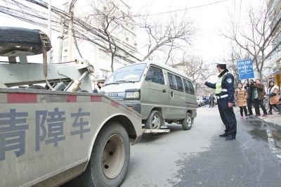 联合执法人员将市民举报的违法占道经营车辆拖走暂扣