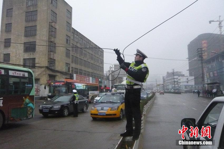 安徽一交警雨中托举电缆让车辆通过